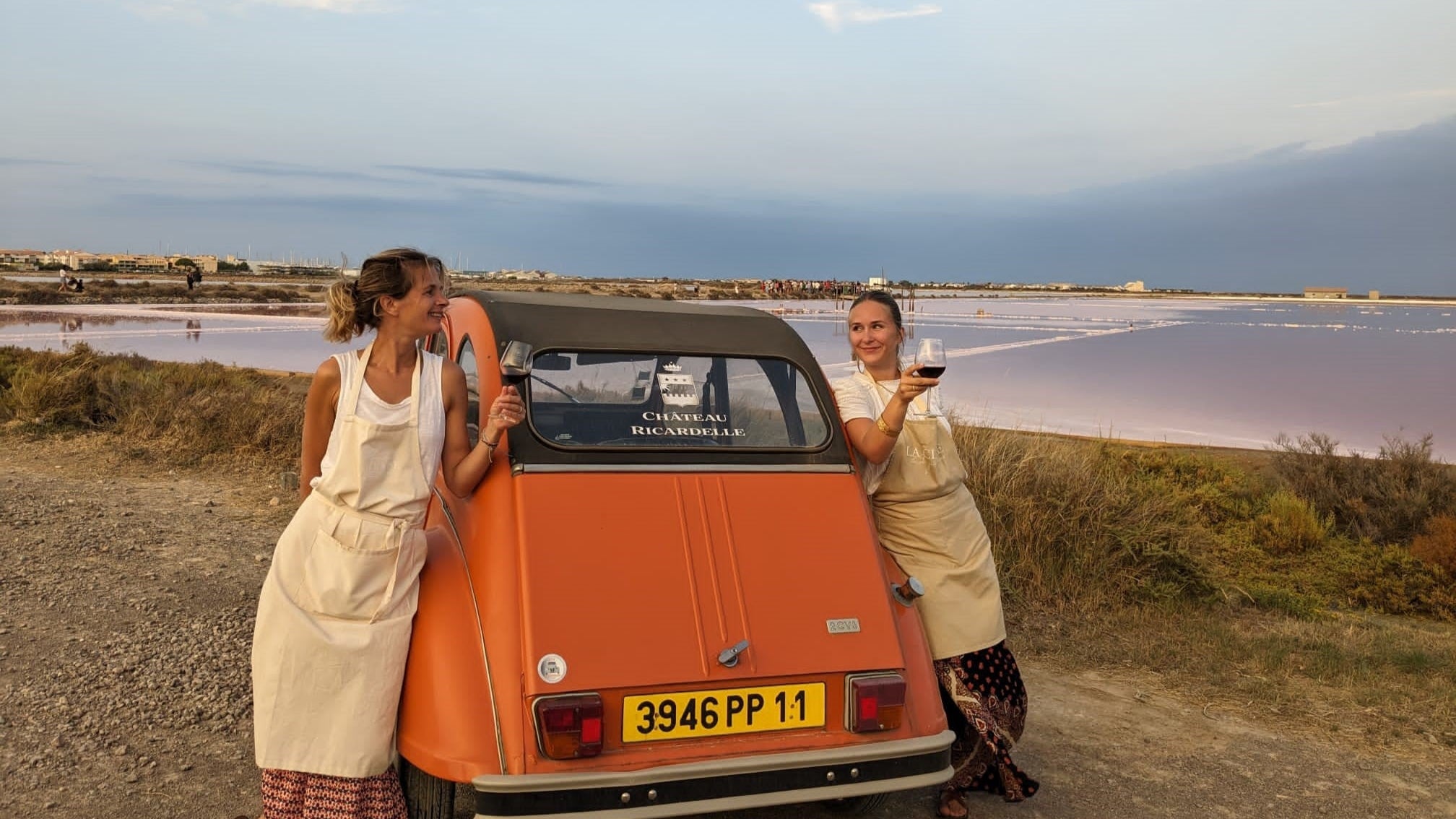 Château Ricardelle Foto mit 2 Frauen die Weingläser halten und an ein rotes Auto lehnen